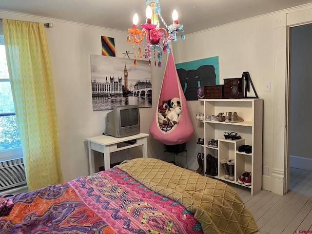 bedroom featuring hardwood / wood-style flooring, crown molding, and an inviting chandelier