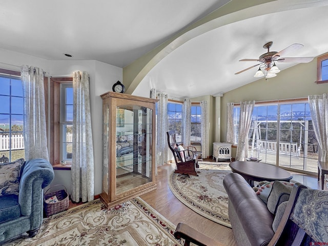 living room featuring vaulted ceiling, ceiling fan, hardwood / wood-style floors, and a wood stove