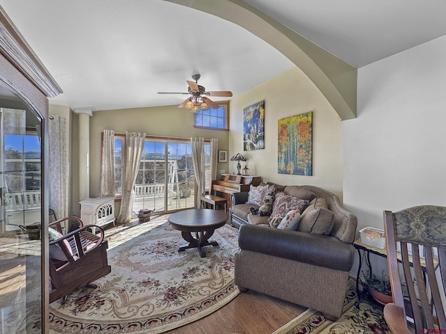 living room featuring lofted ceiling, a wood stove, and ceiling fan