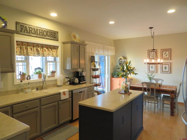 kitchen with sink, stainless steel dishwasher, a kitchen island, pendant lighting, and light hardwood / wood-style floors