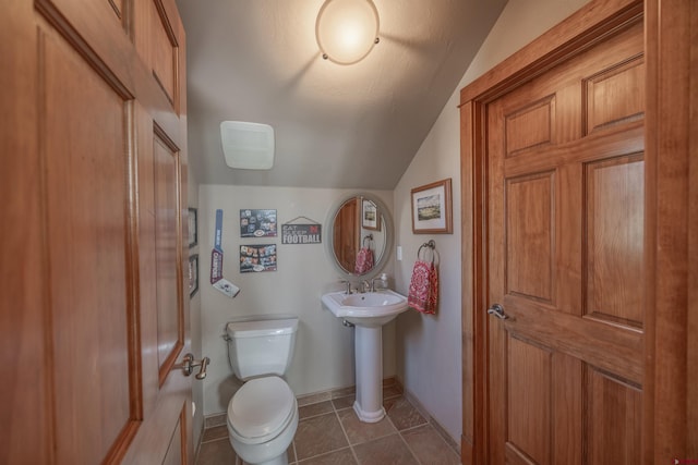 bathroom featuring lofted ceiling, tile patterned floors, and toilet