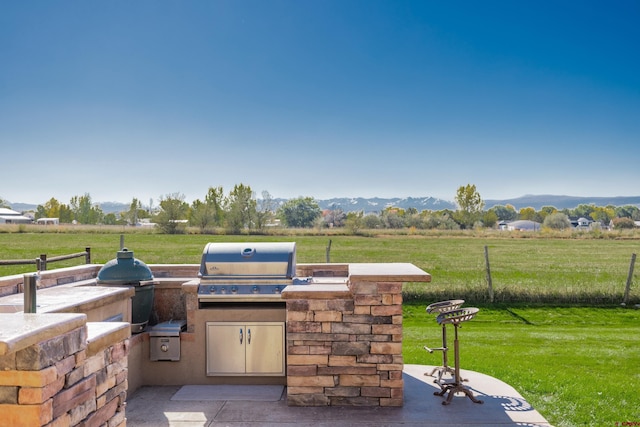 view of patio / terrace with grilling area, an outdoor kitchen, a rural view, and a mountain view