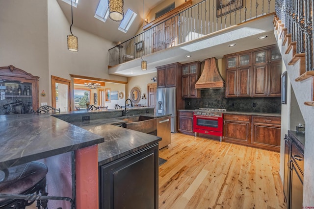 kitchen with hanging light fixtures, custom exhaust hood, stainless steel appliances, and a breakfast bar