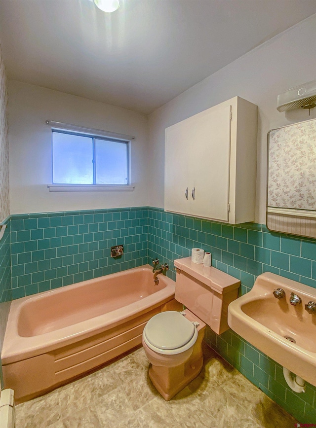 bathroom featuring toilet, a bathing tub, sink, and tile walls