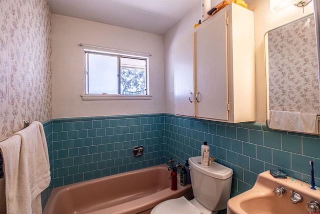 bathroom with tile walls, sink, toilet, and a bathing tub