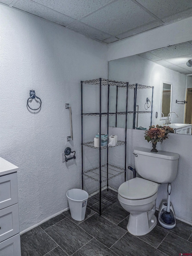 bathroom with vanity, a drop ceiling, and toilet