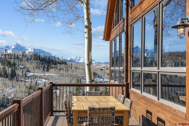 snow covered deck with outdoor dining area and a mountain view