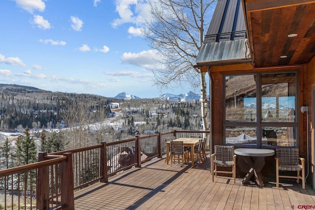 snow covered deck featuring a mountain view and outdoor dining area