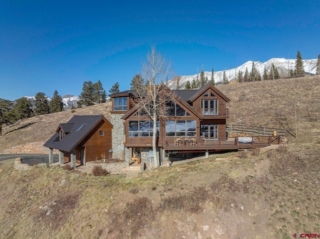 rear view of property featuring a deck with mountain view and metal roof