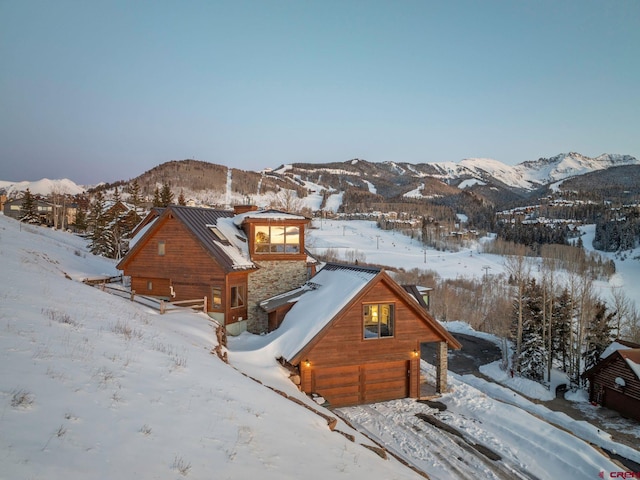 exterior space featuring a garage, stone siding, a mountain view, and metal roof