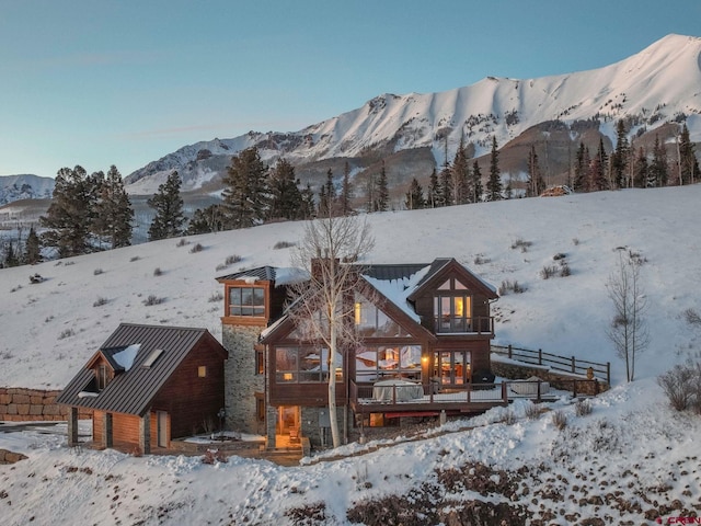 exterior space with a detached garage, a standing seam roof, a mountain view, metal roof, and stone siding