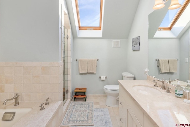 bathroom featuring toilet, a bathing tub, vanity, vaulted ceiling with skylight, and tile patterned floors