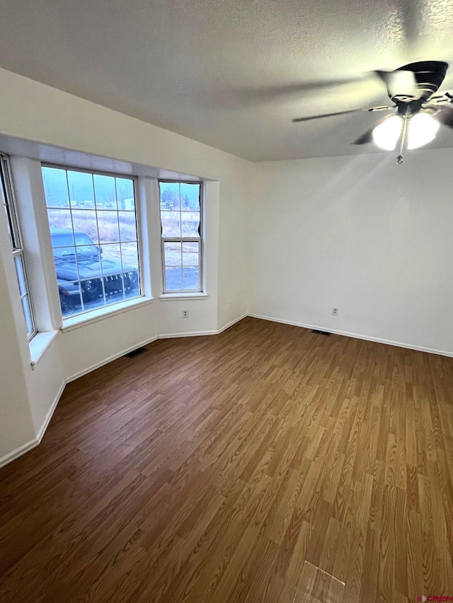 empty room featuring hardwood / wood-style flooring, ceiling fan, and a textured ceiling