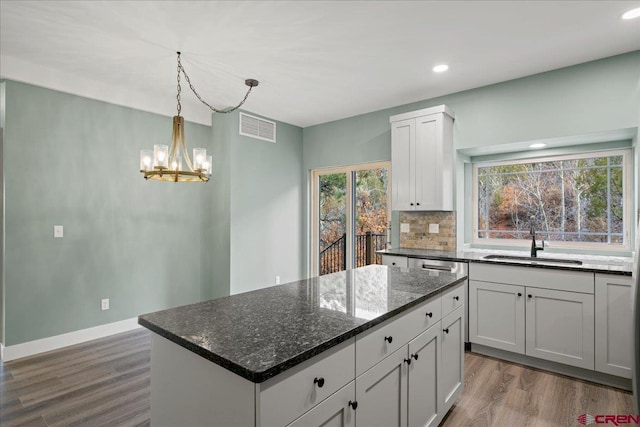 kitchen featuring sink, dark stone countertops, a center island, white cabinets, and decorative backsplash