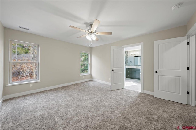 unfurnished bedroom with light carpet, ensuite bath, and ceiling fan