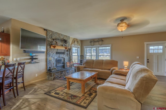 living room with a stone fireplace and light hardwood / wood-style floors