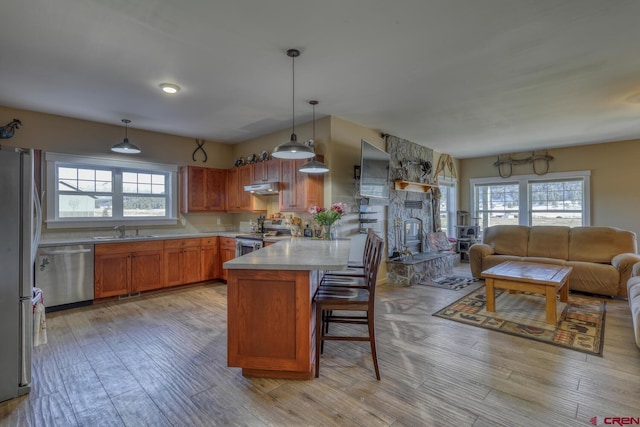 kitchen featuring sink, a breakfast bar, hanging light fixtures, stainless steel appliances, and light wood-type flooring