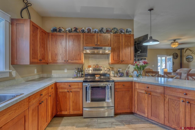 kitchen with decorative light fixtures, light wood-type flooring, kitchen peninsula, and stainless steel electric range oven