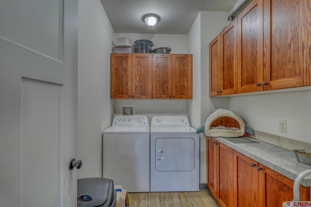 washroom featuring separate washer and dryer, cabinets, and light wood-type flooring