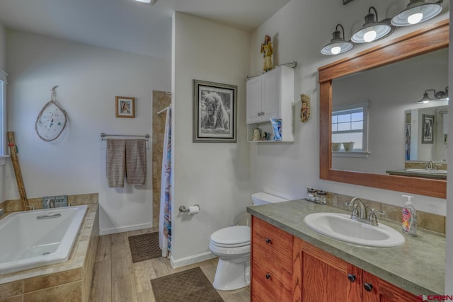 bathroom featuring vanity, tiled tub, hardwood / wood-style flooring, and toilet