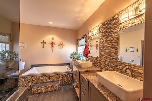 bathroom with vanity, tiled bath, and decorative backsplash