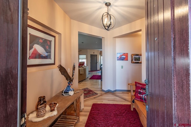 corridor featuring an inviting chandelier and light hardwood / wood-style floors