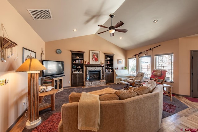 living room featuring vaulted ceiling, a stone fireplace, and ceiling fan