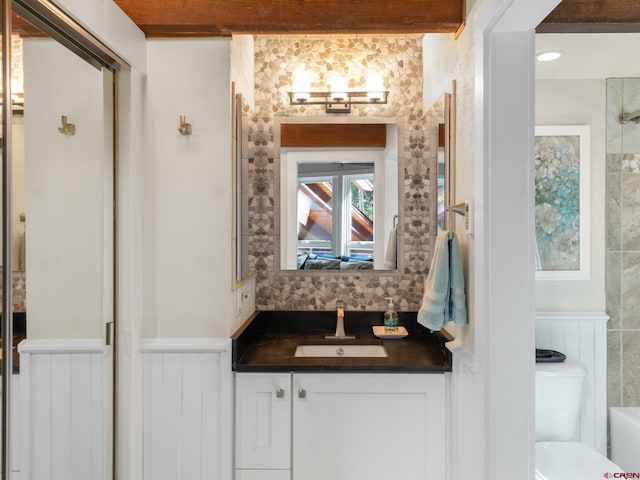 bathroom featuring vanity, toilet, and beam ceiling