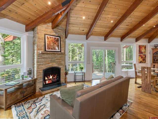 living room with vaulted ceiling with beams, wood ceiling, a fireplace, and light hardwood / wood-style flooring