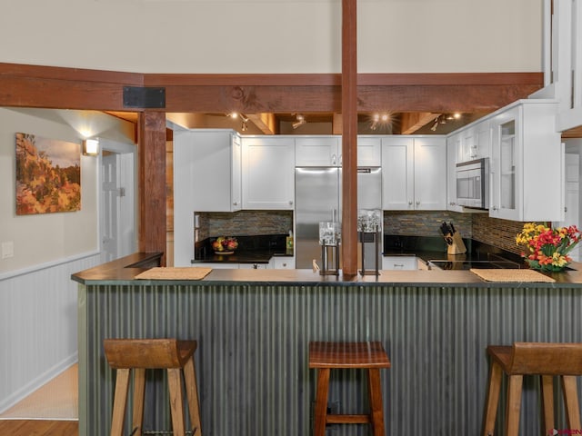 kitchen featuring a breakfast bar area, stainless steel appliances, kitchen peninsula, and white cabinets