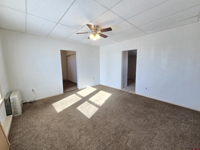 carpeted spare room with ceiling fan, an AC wall unit, and a drop ceiling