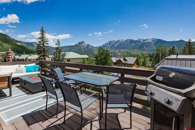 wooden deck featuring area for grilling, a mountain view, and an outdoor living space with a fire pit