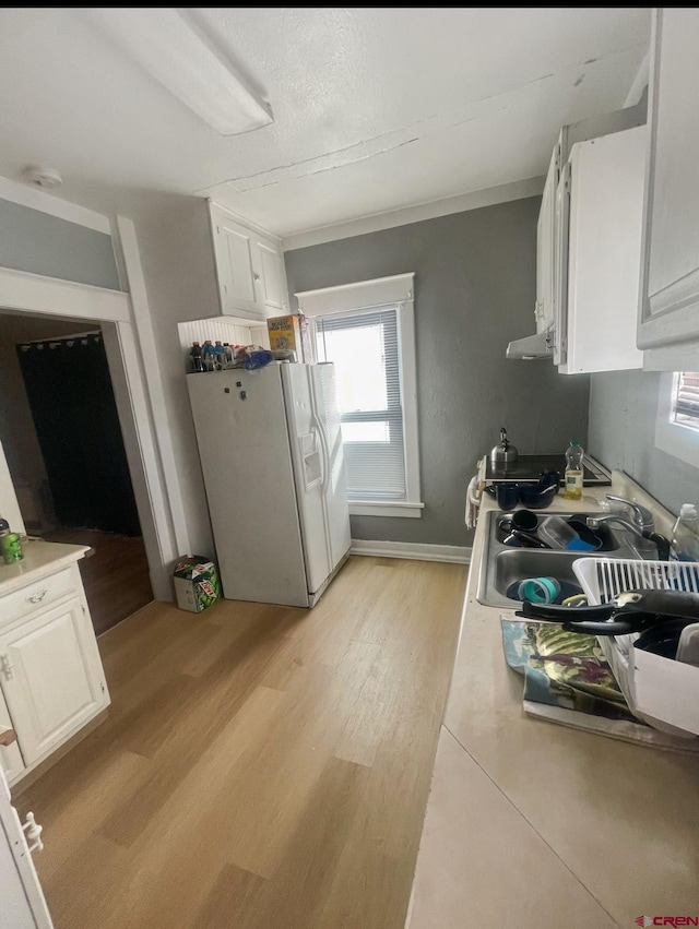 kitchen featuring white fridge with ice dispenser, sink, white cabinets, and light wood-type flooring