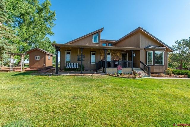 view of front facade with a shed, a front yard, and covered porch