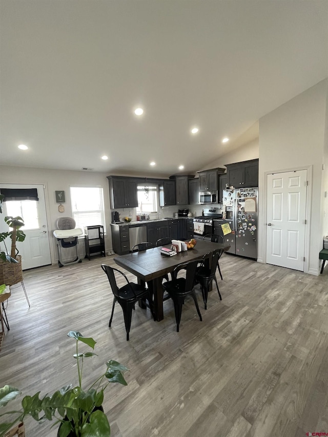 dining room with lofted ceiling and light wood-type flooring