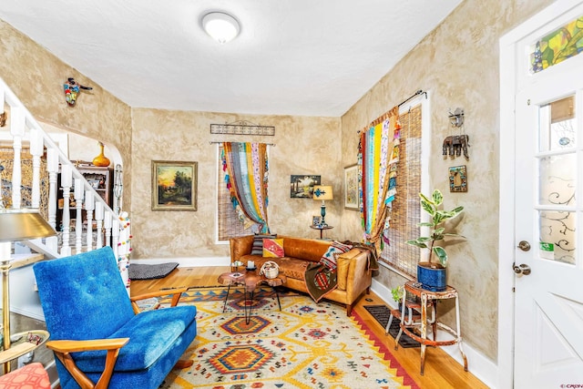 sitting room featuring baseboards, arched walkways, stairs, and wood finished floors