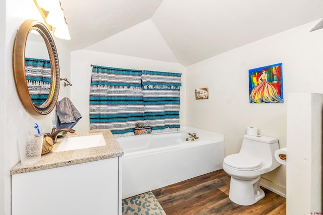 bathroom featuring vanity, wood finished floors, toilet, a bath, and vaulted ceiling