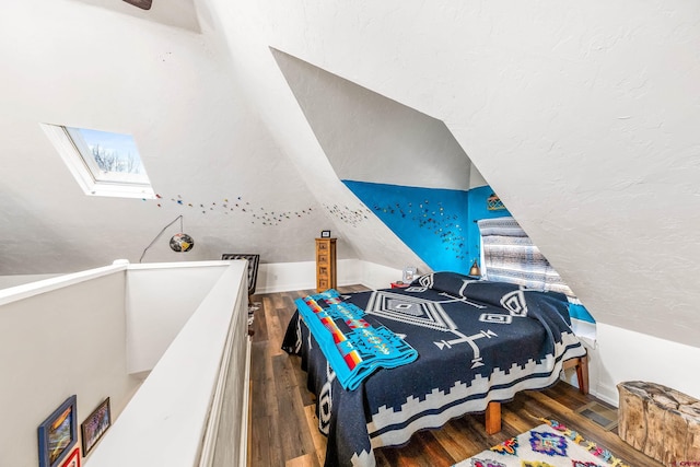 bedroom featuring visible vents, wood finished floors, and vaulted ceiling with skylight