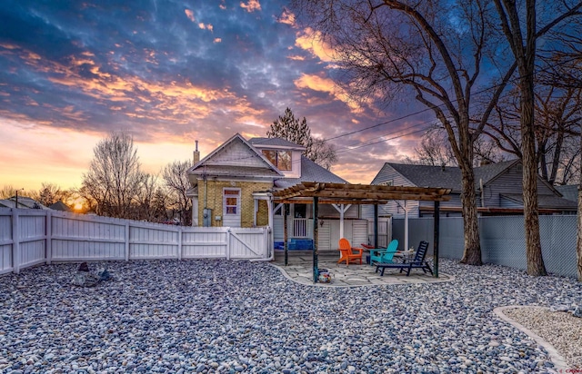 back of property at dusk with a pergola, a fenced backyard, a gate, a chimney, and a patio area
