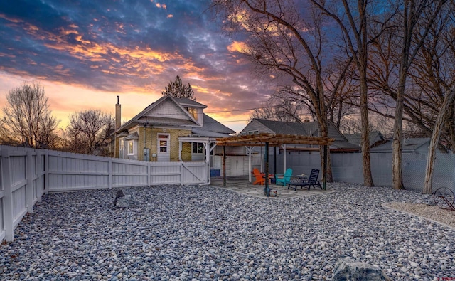 back of property at dusk with brick siding, a pergola, a fenced backyard, and a patio area