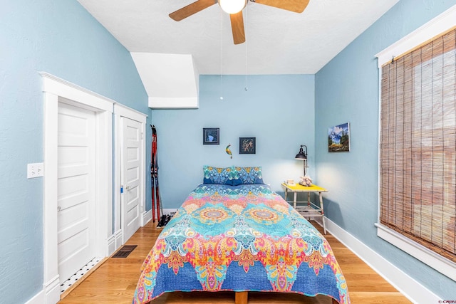 bedroom with a ceiling fan, baseboards, visible vents, and wood finished floors