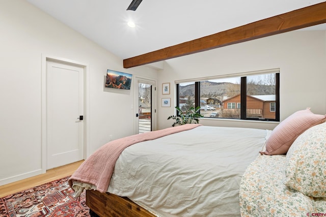 bedroom with ceiling fan, vaulted ceiling with beams, and light wood-type flooring