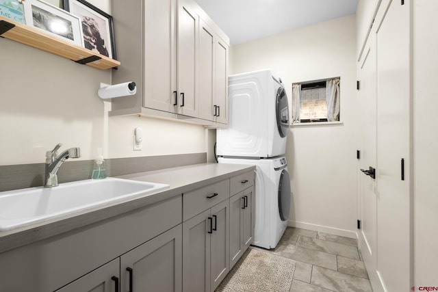 laundry room with stacked washer / dryer, sink, and cabinets