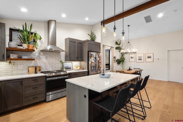 kitchen featuring a breakfast bar area, light hardwood / wood-style flooring, appliances with stainless steel finishes, a kitchen island, and range hood