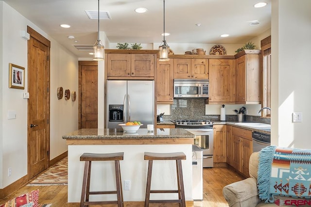 kitchen featuring decorative light fixtures, sink, a center island, light hardwood / wood-style floors, and stainless steel appliances