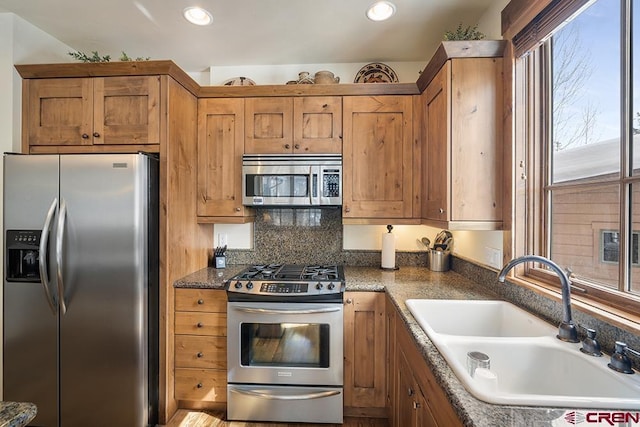kitchen with appliances with stainless steel finishes, sink, and dark stone counters