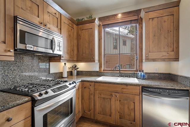 kitchen featuring tasteful backsplash, sink, stainless steel appliances, and dark stone counters