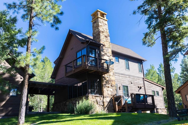 back of house with a wooden deck, a balcony, and a yard