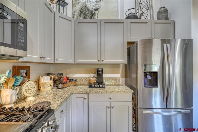 kitchen with white cabinetry, light stone countertops, and appliances with stainless steel finishes