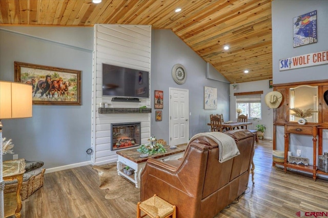 living room with hardwood / wood-style flooring, high vaulted ceiling, a large fireplace, and wood ceiling